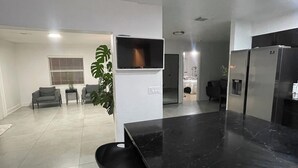 Una cocina moderna con encimera de mármol negro, televisor integrado y una planta en maceta.