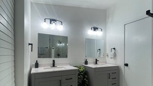 Un baño con dos lavamanos, espejos y un perchero para toallas.