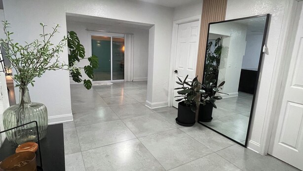 Una habitación amplia con suelo de baldosas, un espejo grande y plantas en macetas.