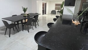 Una cocina moderna con encimera de mármol negro y un comedor con mesa y sillas.
