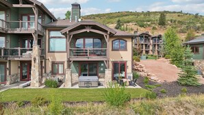 Un edificio de varios pisos con fachada de piedra, balcones y un patio con mobiliario exterior.