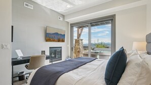 Un hotel moderno con una cama grande, un escritorio, una silla y vistas a la montaña a través de un ventanal amplio.