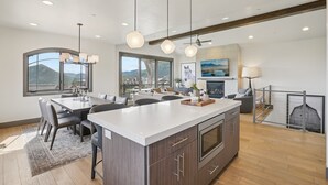 Una cocina amplia con una isla grande, lámparas colgantes modernas y vistas a la montaña.