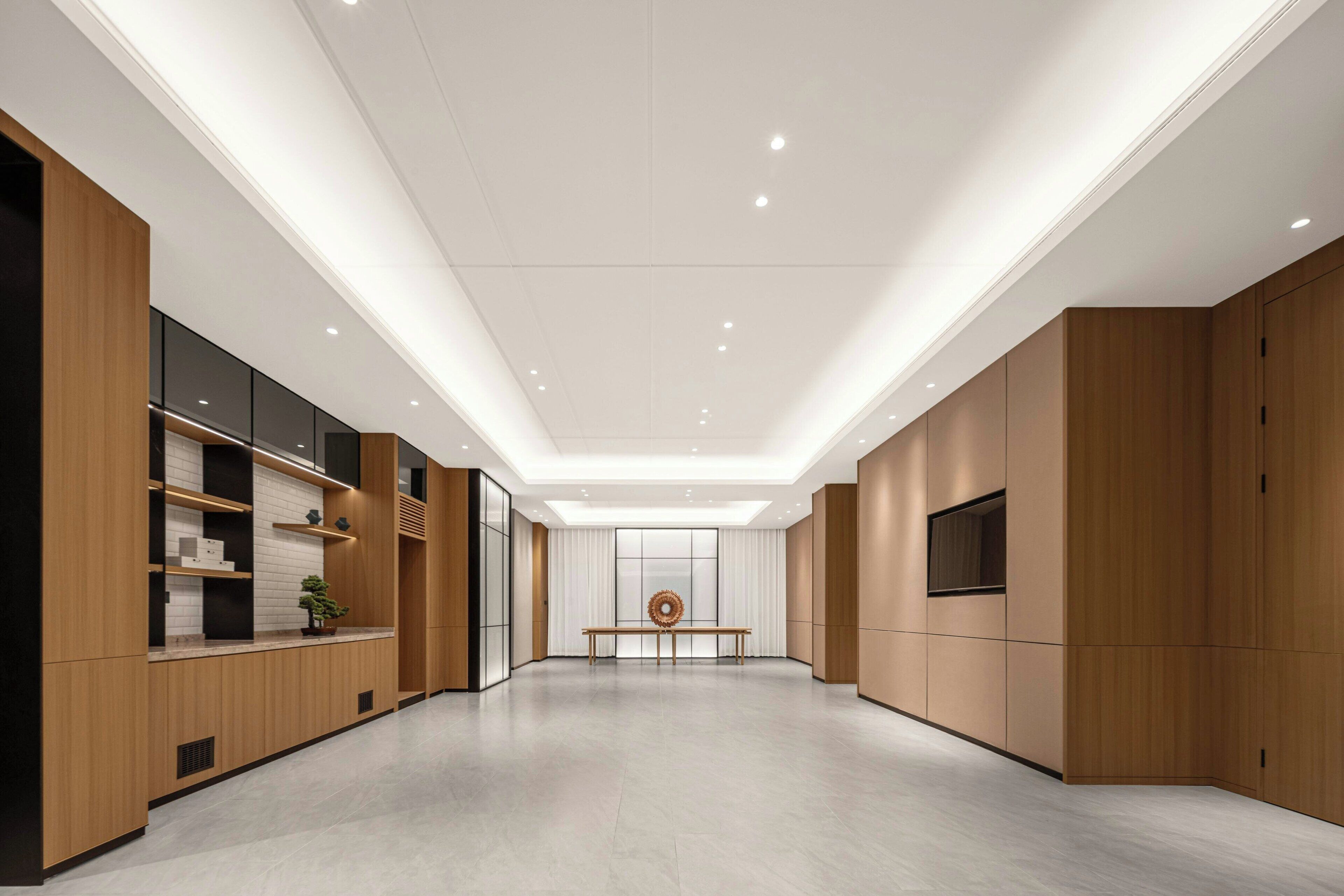Un interior espacioso y moderno con paneles de madera, un área de estar central e iluminación empotrada.