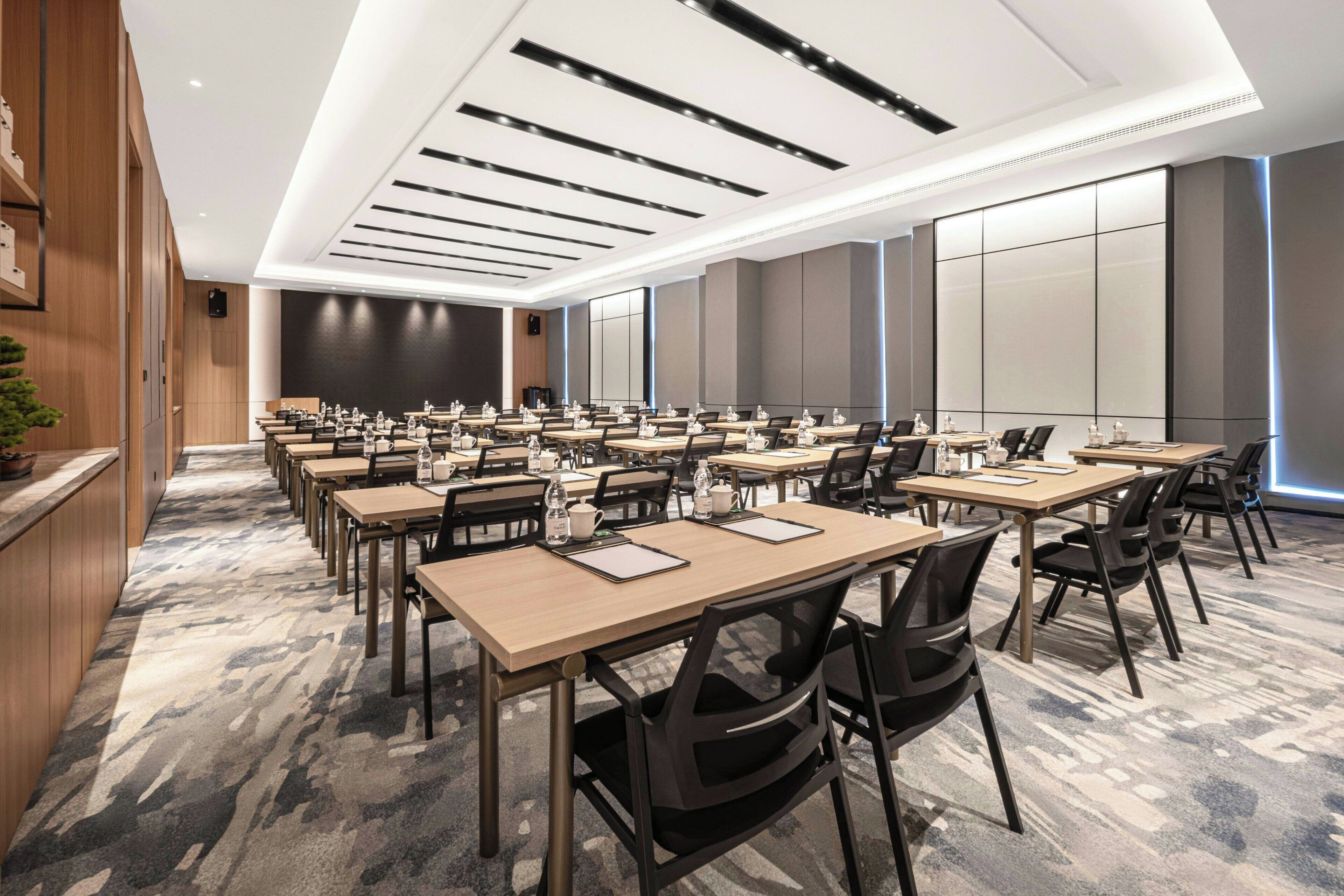 A conference room with multiple tables and chairs, equipped with water bottles and notepads.