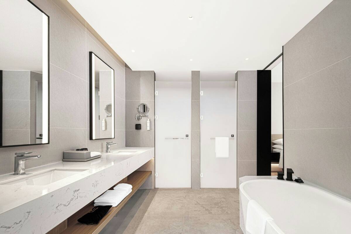 Ein modernes Badezimmer mit zwei Waschbecken, einem großen Spiegel und einer Badewanne.
