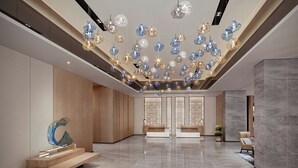 A spacious lobby with a modern design, featuring a marble floor, a central seating area, and a unique ceiling installation with spherical light fixtures. - Fairfield By Marriott Yinchuan Xingqing (Yinchuan)