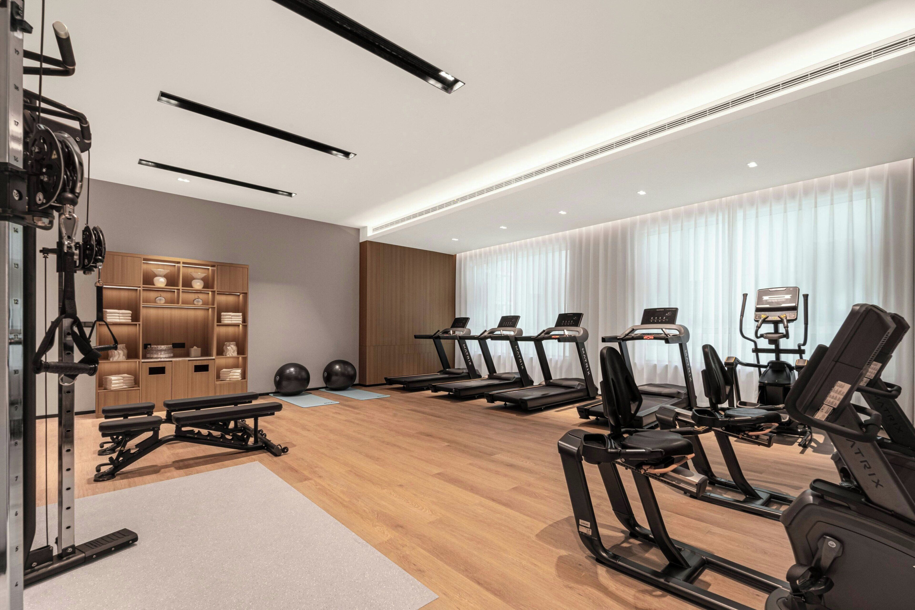 Un gimnasio moderno con cintas de correr, una banca de pesas y una jaula de sentadillas.