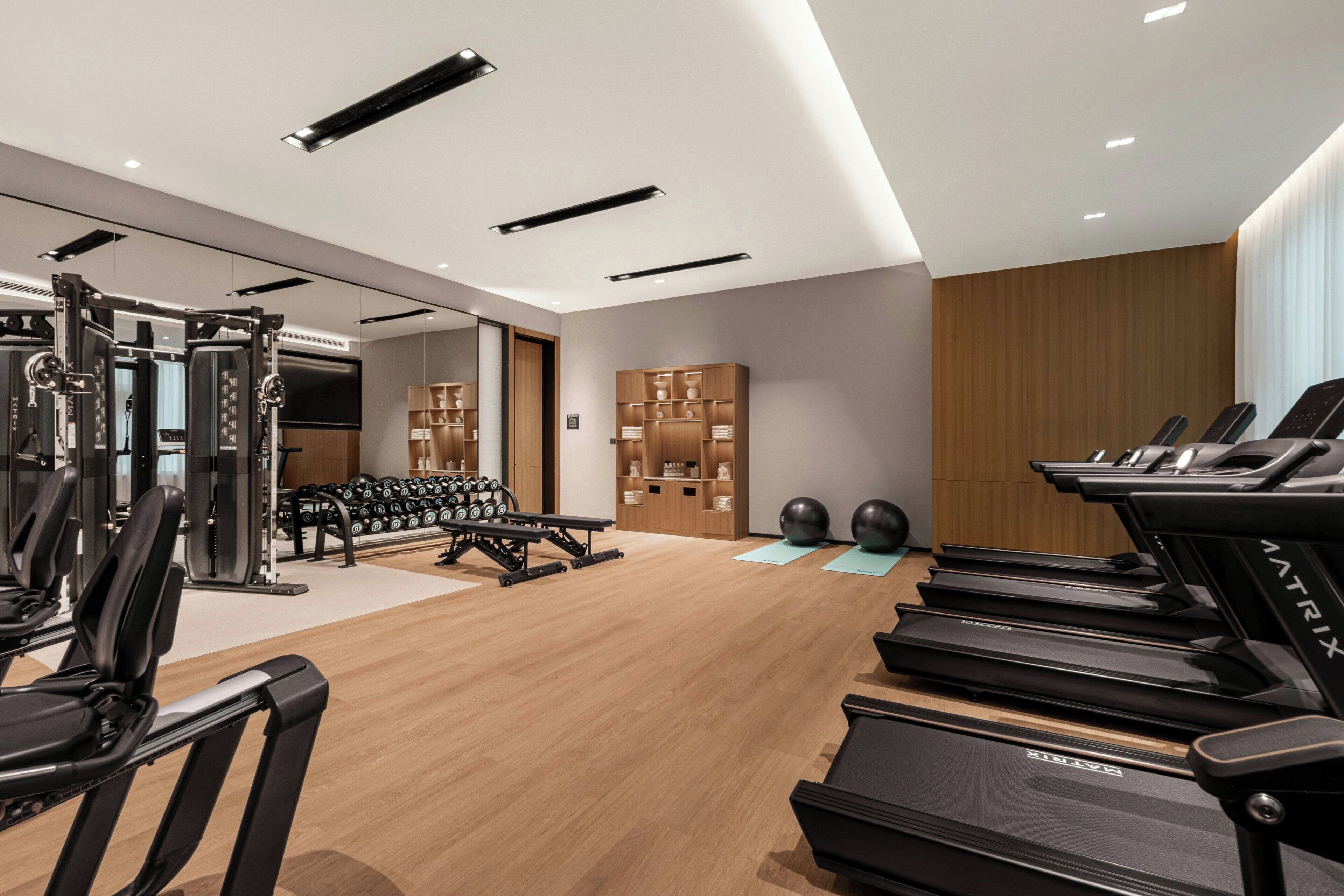 A modern gym with treadmills, weight machines, and free weights.