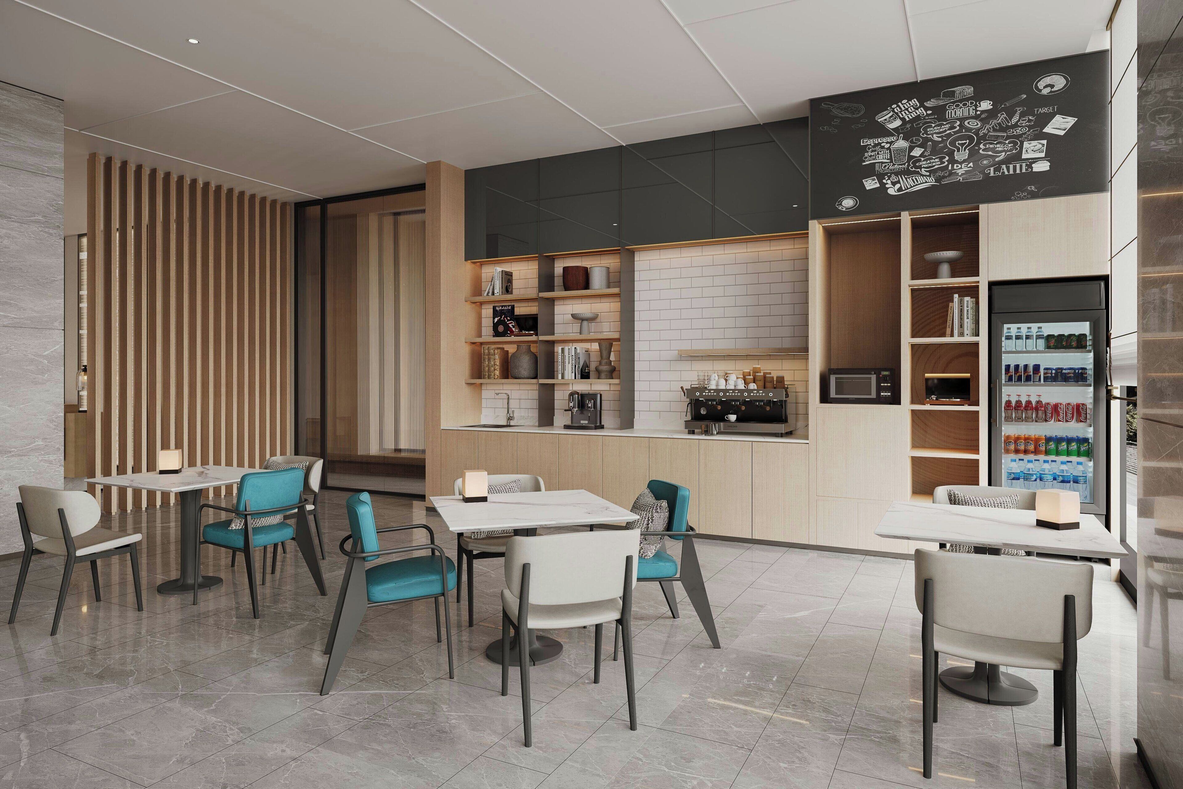 A modern cafe with a clean, minimalist design, featuring a central dining area with white tables and teal chairs, a coffee bar with a refrigerator stocked with beverages, and a chalkboard wall with various doodles.