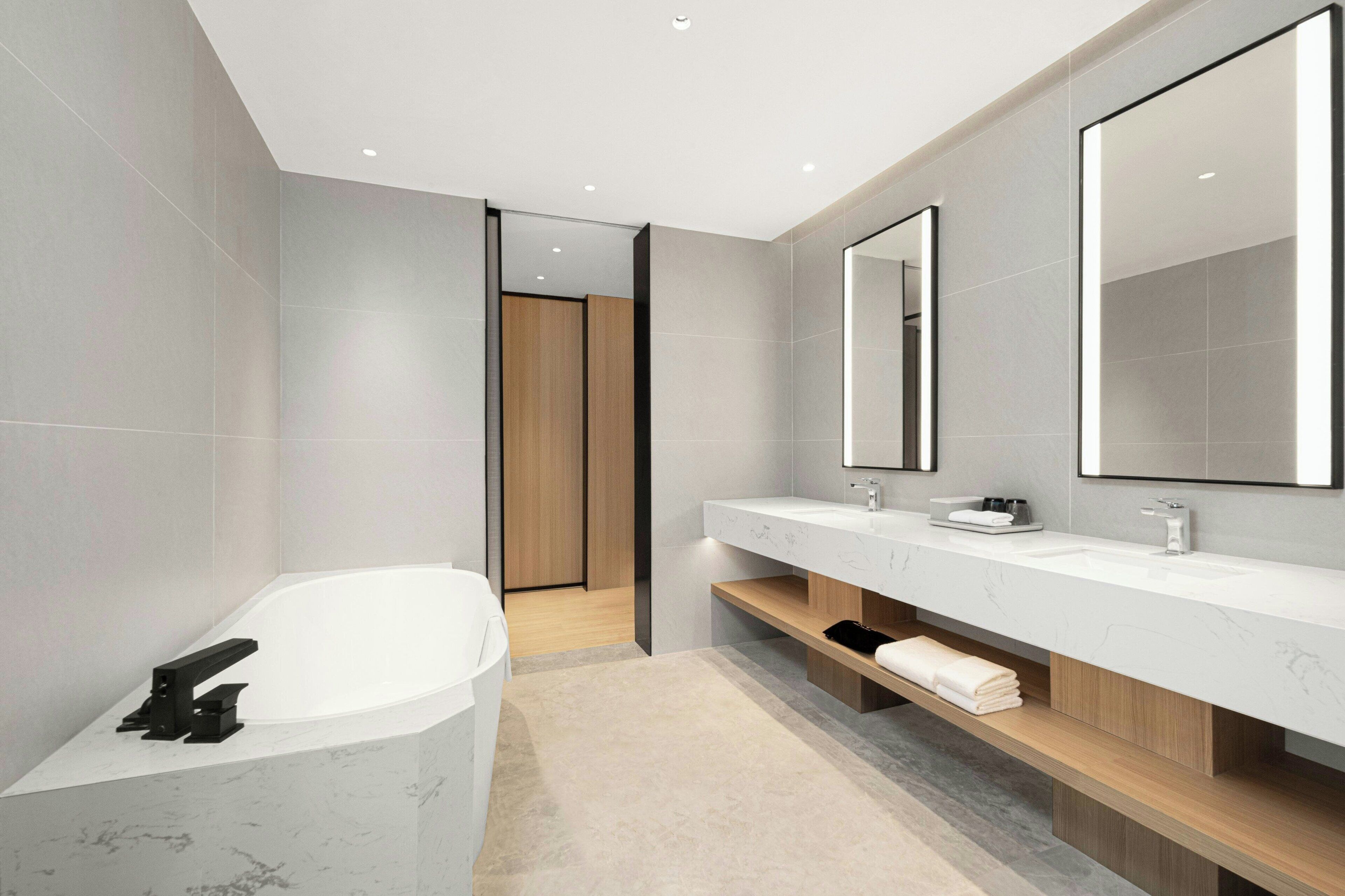 Une salle de bain moderne avec une baignoire sur pieds, un grand miroir et un meuble-lavabo doté d’un plan de travail en marbre.