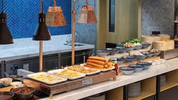 Un bufé con diversos platos y una cocina moderna al fondo.