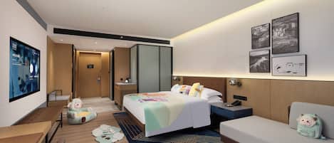 A modern hotel room with a large bed, a sofa, a desk, and a TV.