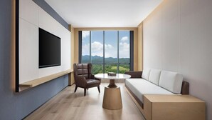 Una sala de estar moderna con un televisor grande, un sofá, un sillón y una mesita de centro.