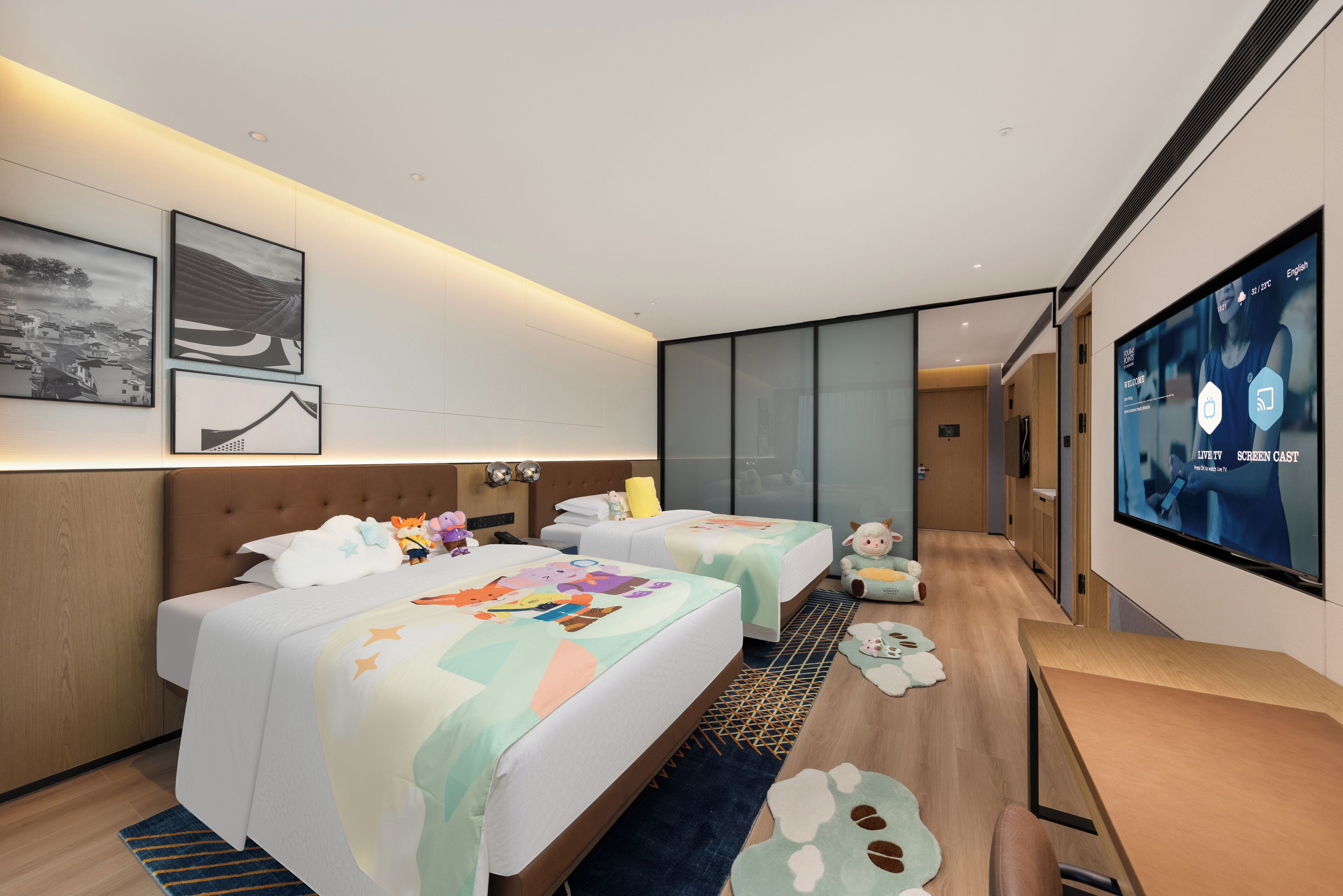 Une chambre d’hôtel moderne avec deux lits, une grande télévision et des œuvres d’art accrochées au mur.