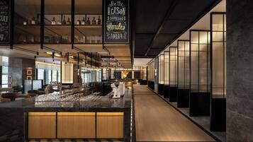 A modern bar area with a long counter, bar stools, and a large selection of bottles on shelves.