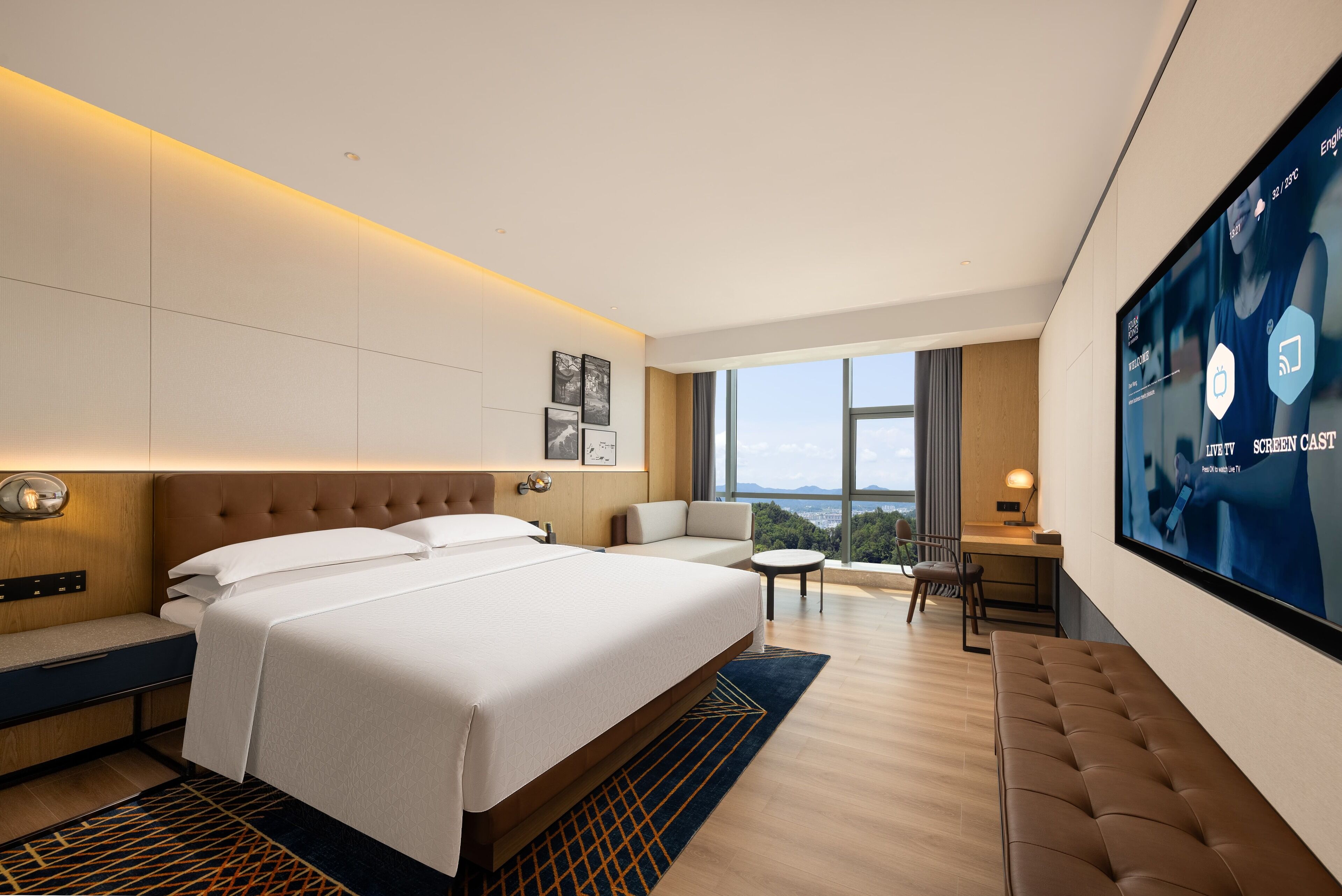 A modern hotel room with a large bed, a desk, and a TV displaying a screen.