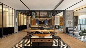 Un moderno vestíbulo de hotel con barra central, zonas de estar y mostrador de recepción.