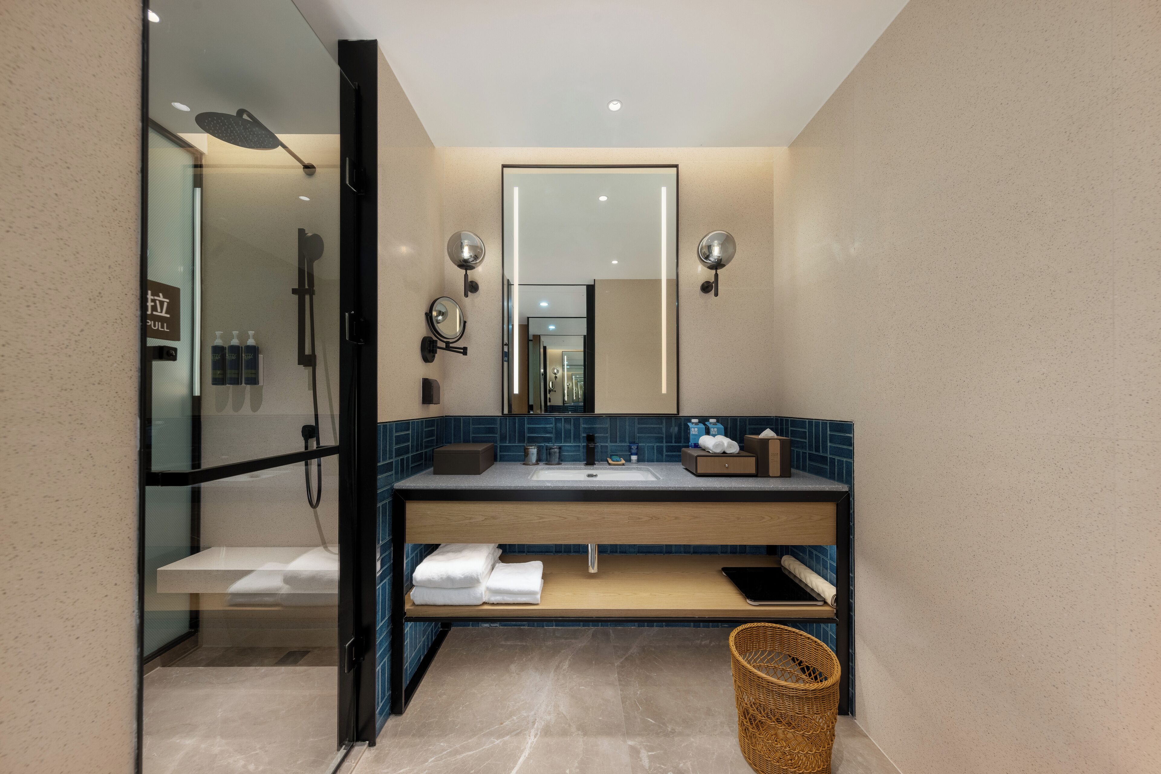 Un baño moderno con cabina de ducha de vidrio, un espejo grande y un mueble de tocador de madera con lavabo.
