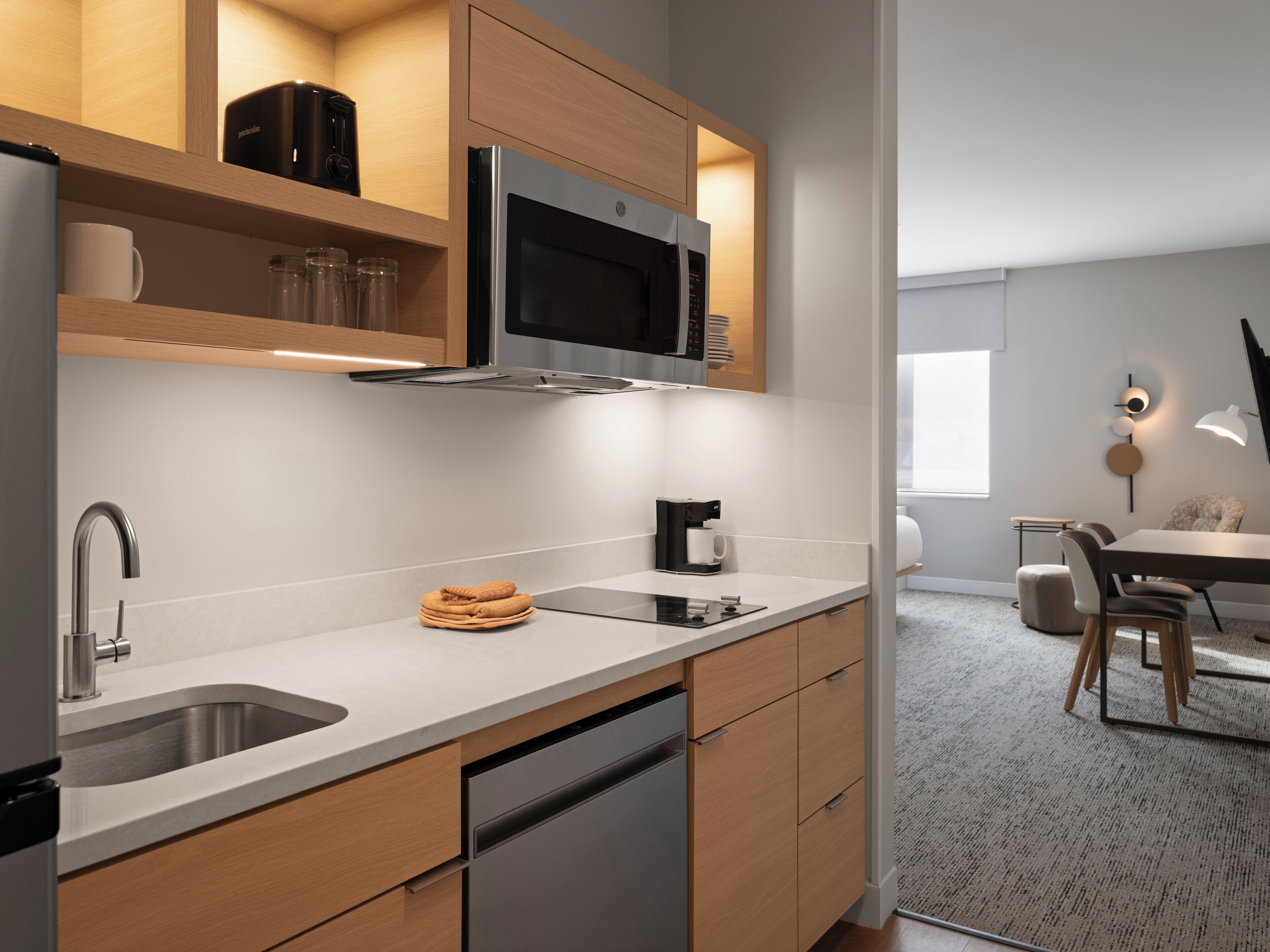 A modern kitchen with stainless steel appliances, wooden cabinets, and a built-in microwave.