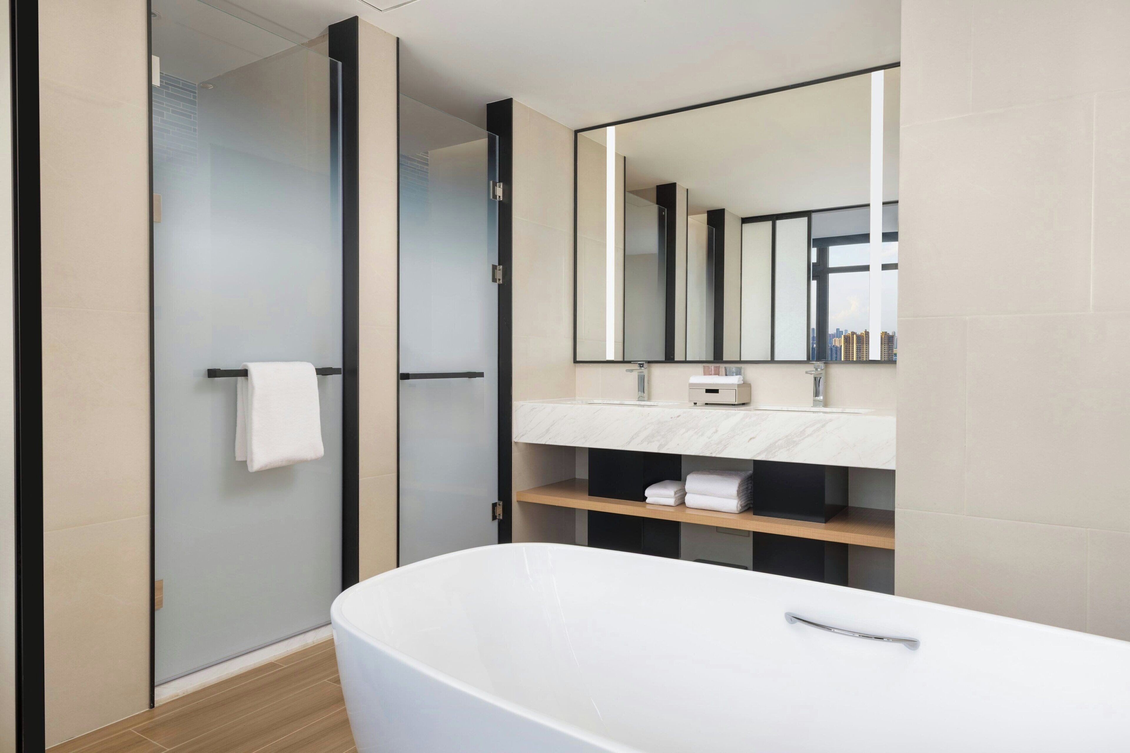A modern bathroom with a large bathtub, a glass shower enclosure, and a vanity with a mirror.