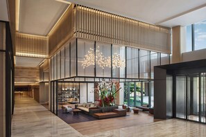 Un'ampia hall dall'arredamento moderno, con una zona relax dotata di divani e una composizione floreale decorativa.