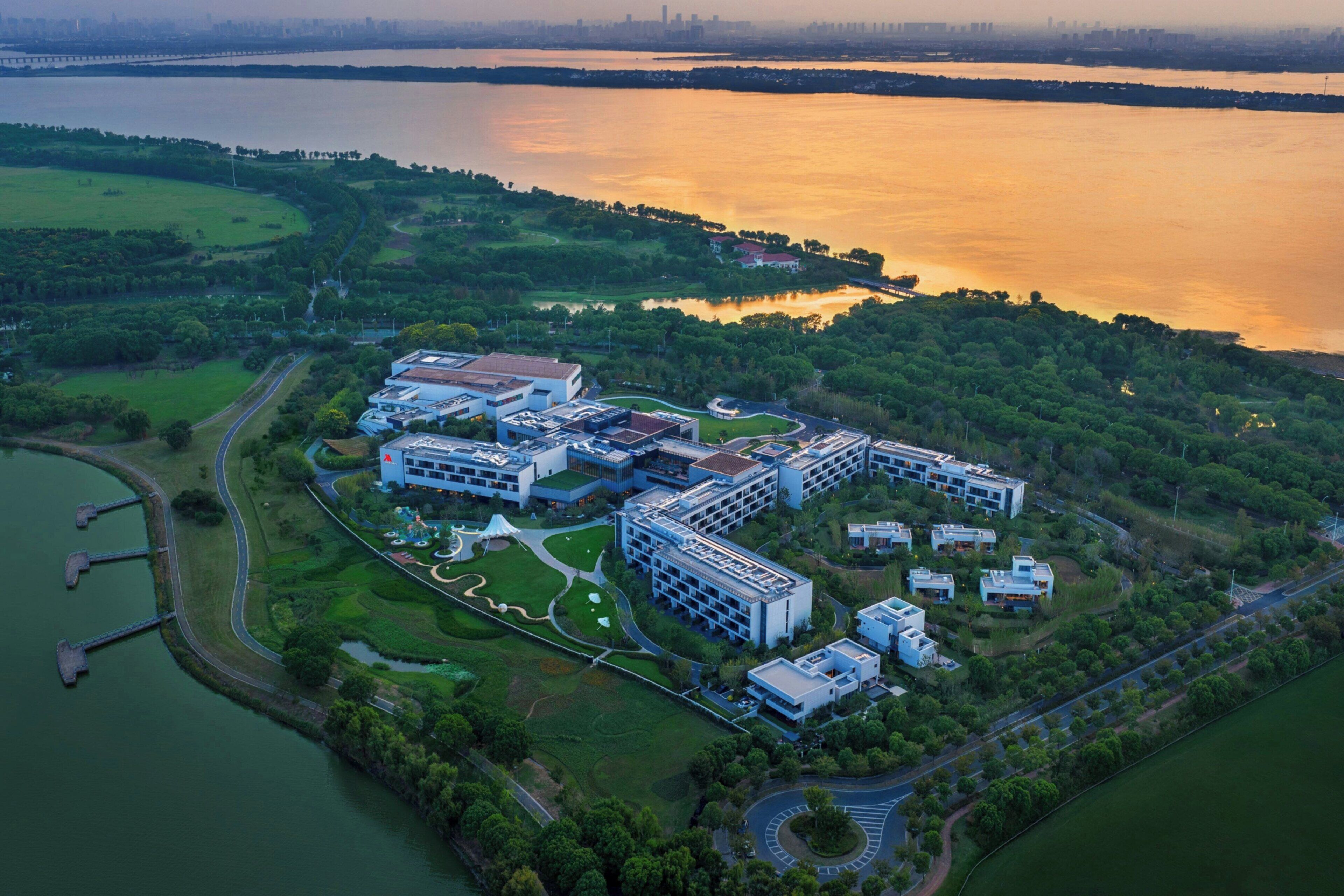 Vista aérea de un campus moderno con varios edificios, un lago y un puente.