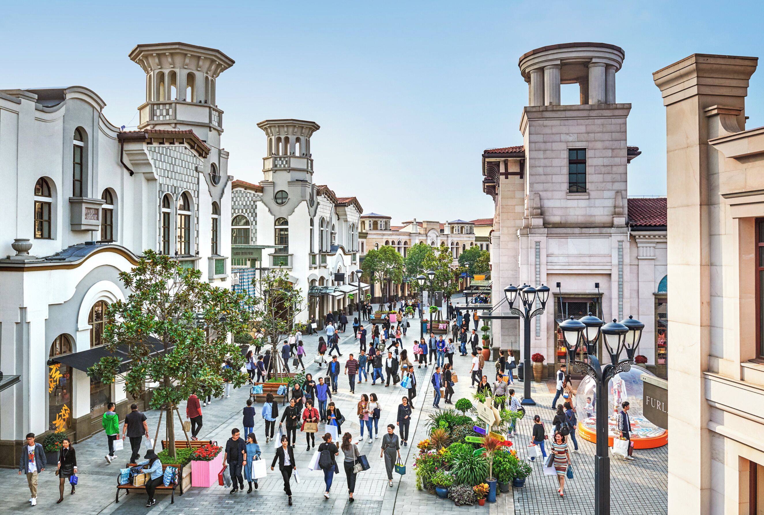 A bustling urban square with historic architecture, including a prominent clock tower and classical columns.