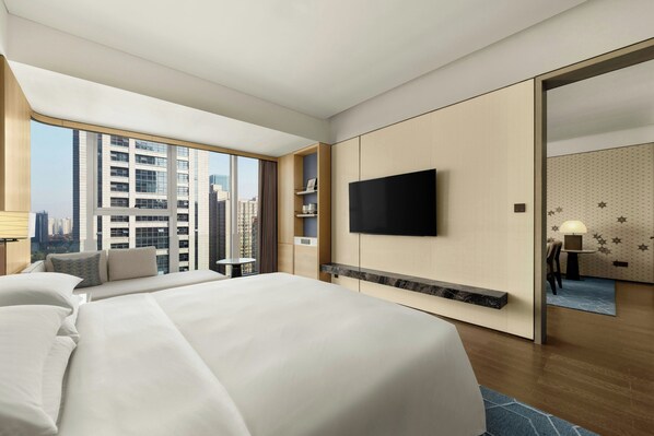 A modern hotel room with a large bed, a flat-screen TV, a small table, and a view of the cityscape through large windows. - Xi'An Marriott Hotel High-Tech Zone (Xi'an)