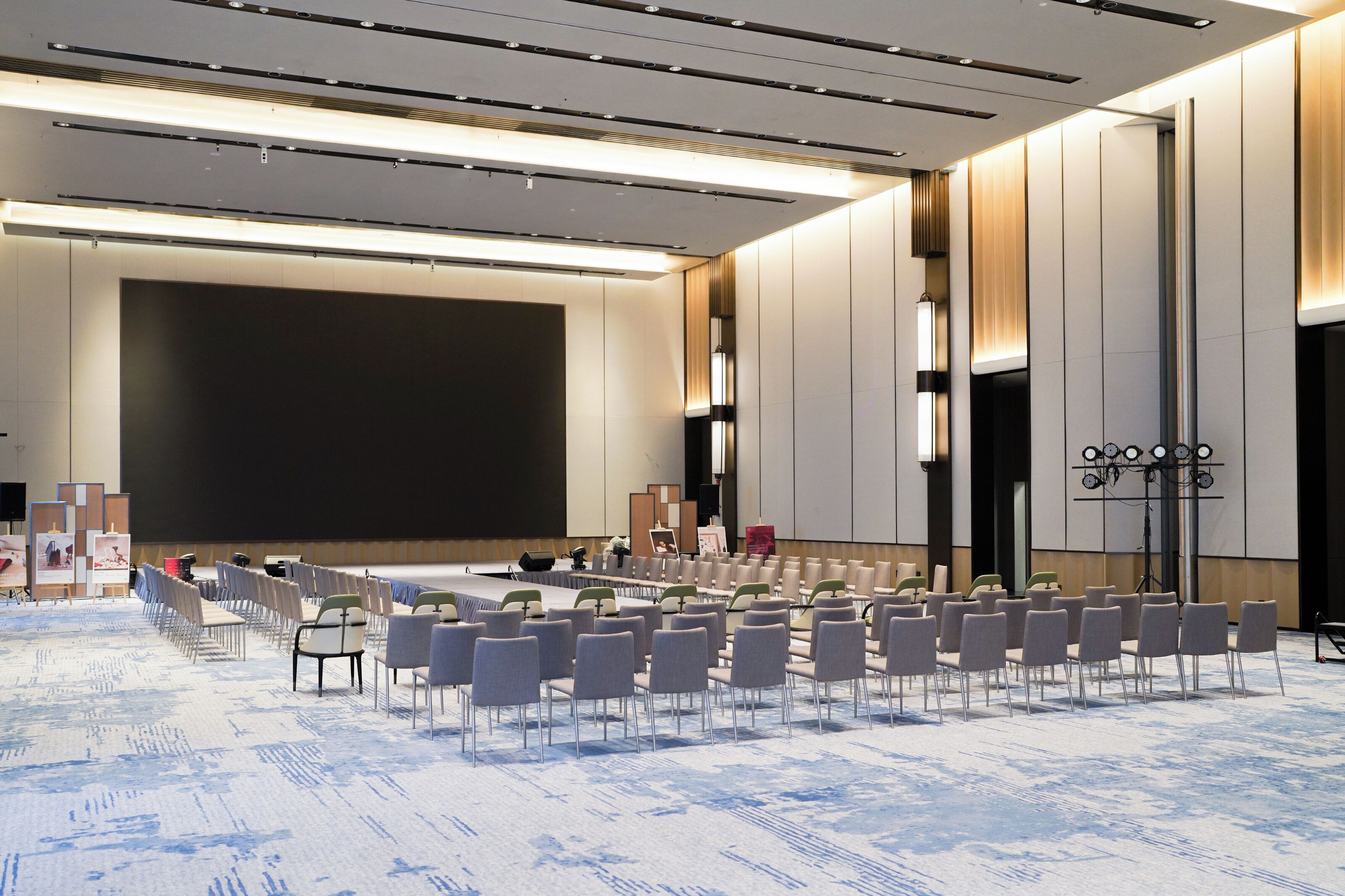 A conference room with rows of chairs, a large screen, and a podium.