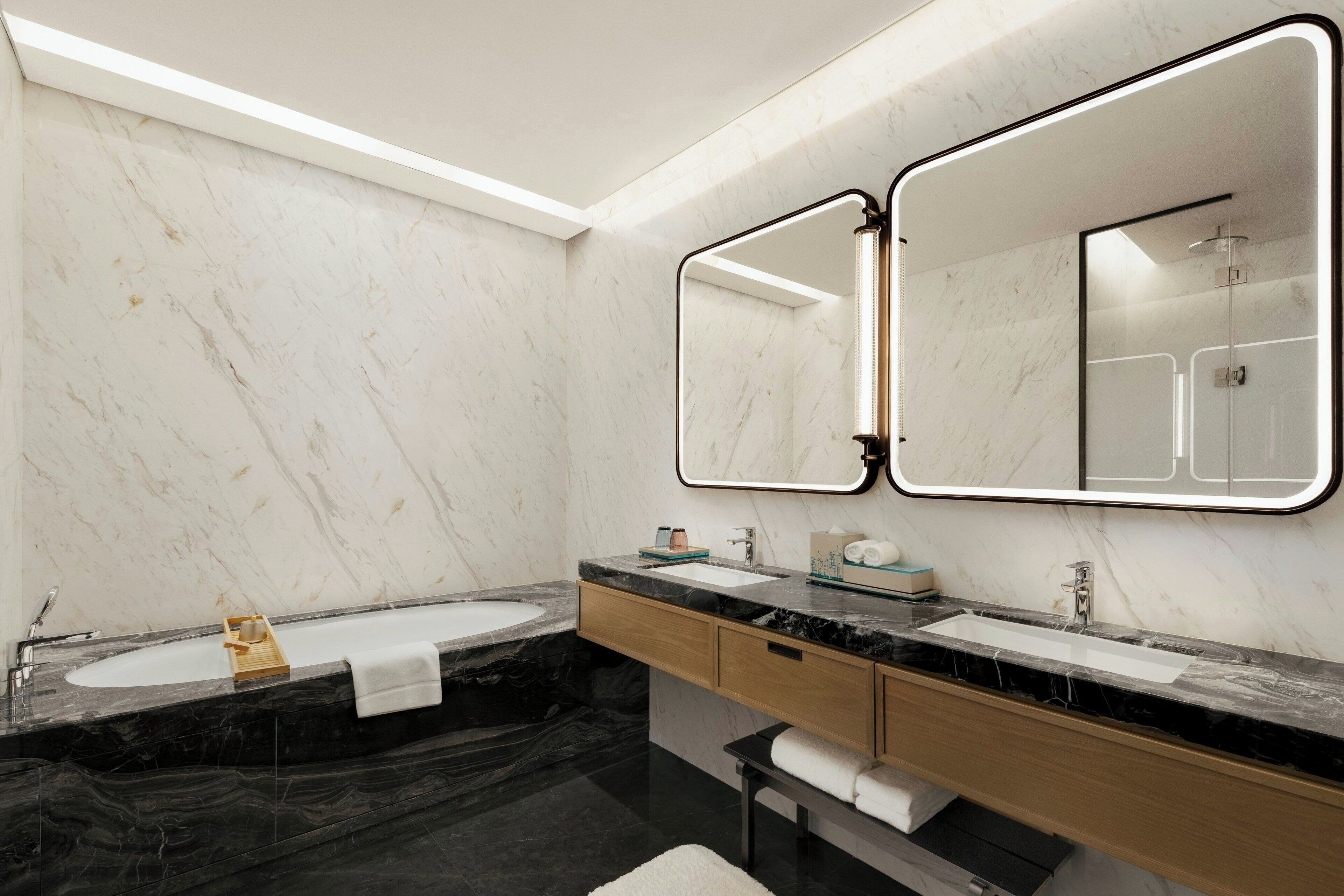 Un baño moderno con dos lavamanos, encimeras de mármol y un espejo grande.