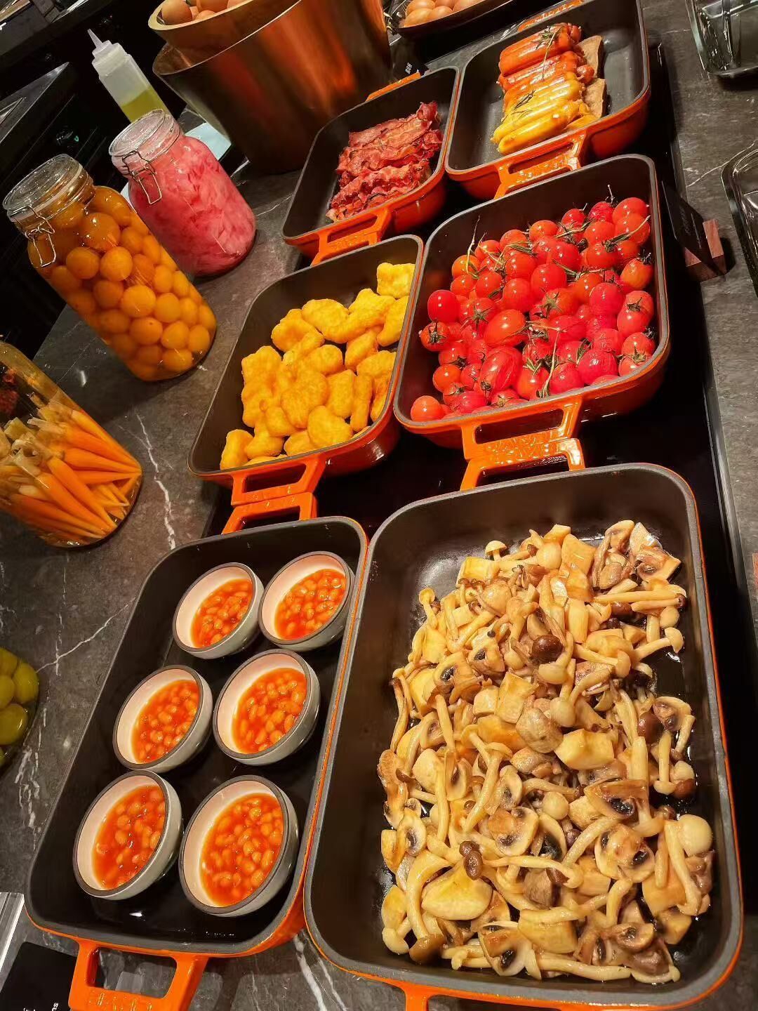 A buffet with various food items including stuffed vegetables, cherry tomatoes, and beans.