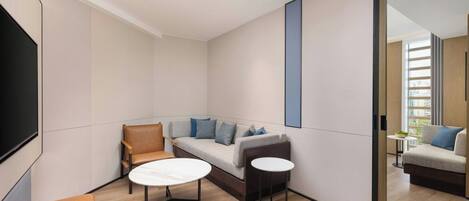 Una habitación moderna con un sofá, dos sillones, una mesita y un espejo grande.