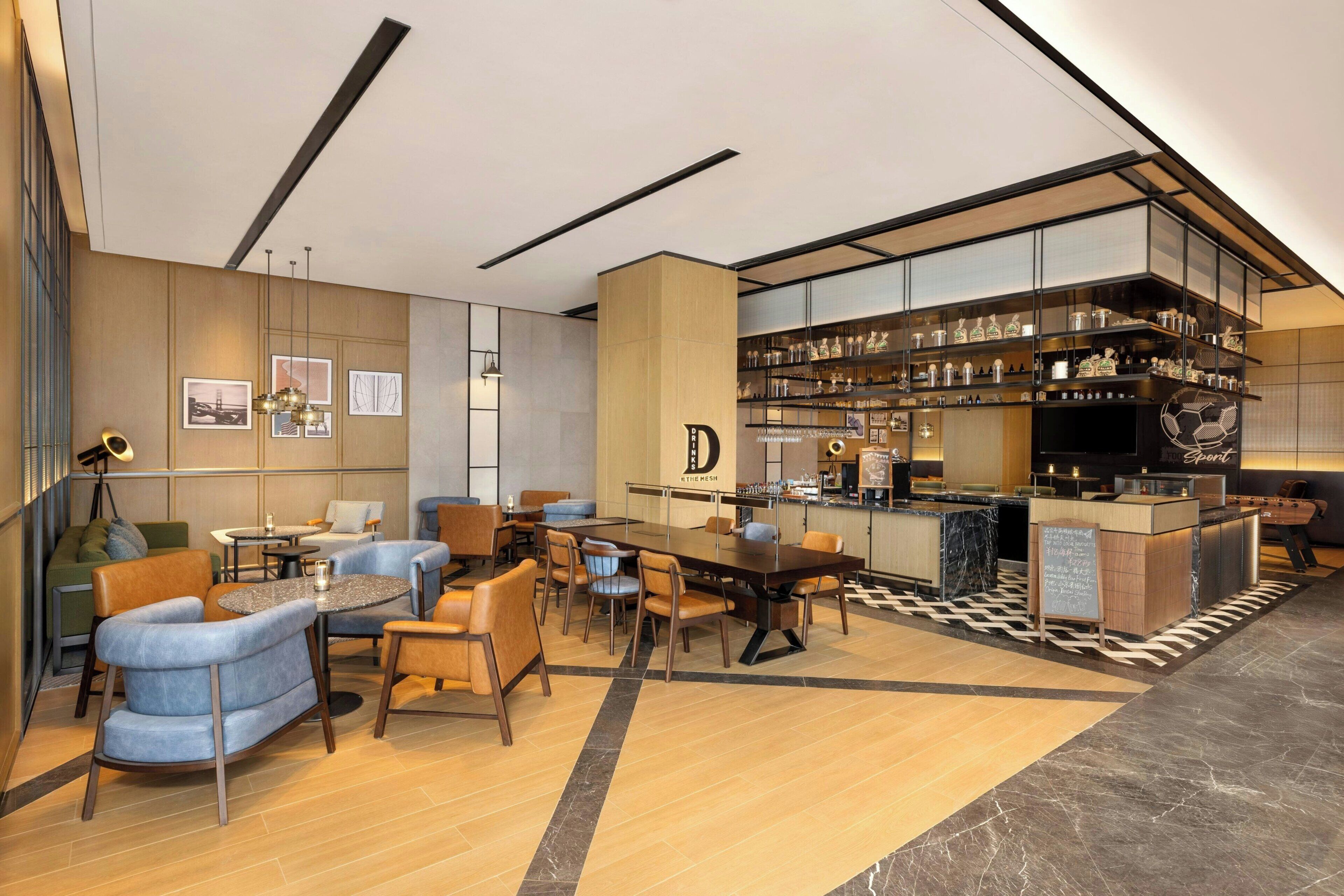 Un moderno vestíbulo de hotel con zona de bar, asientos y mostrador de recepción.
