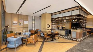 Un moderno vestíbulo de hotel con zona de bar, asientos y mostrador de recepción.