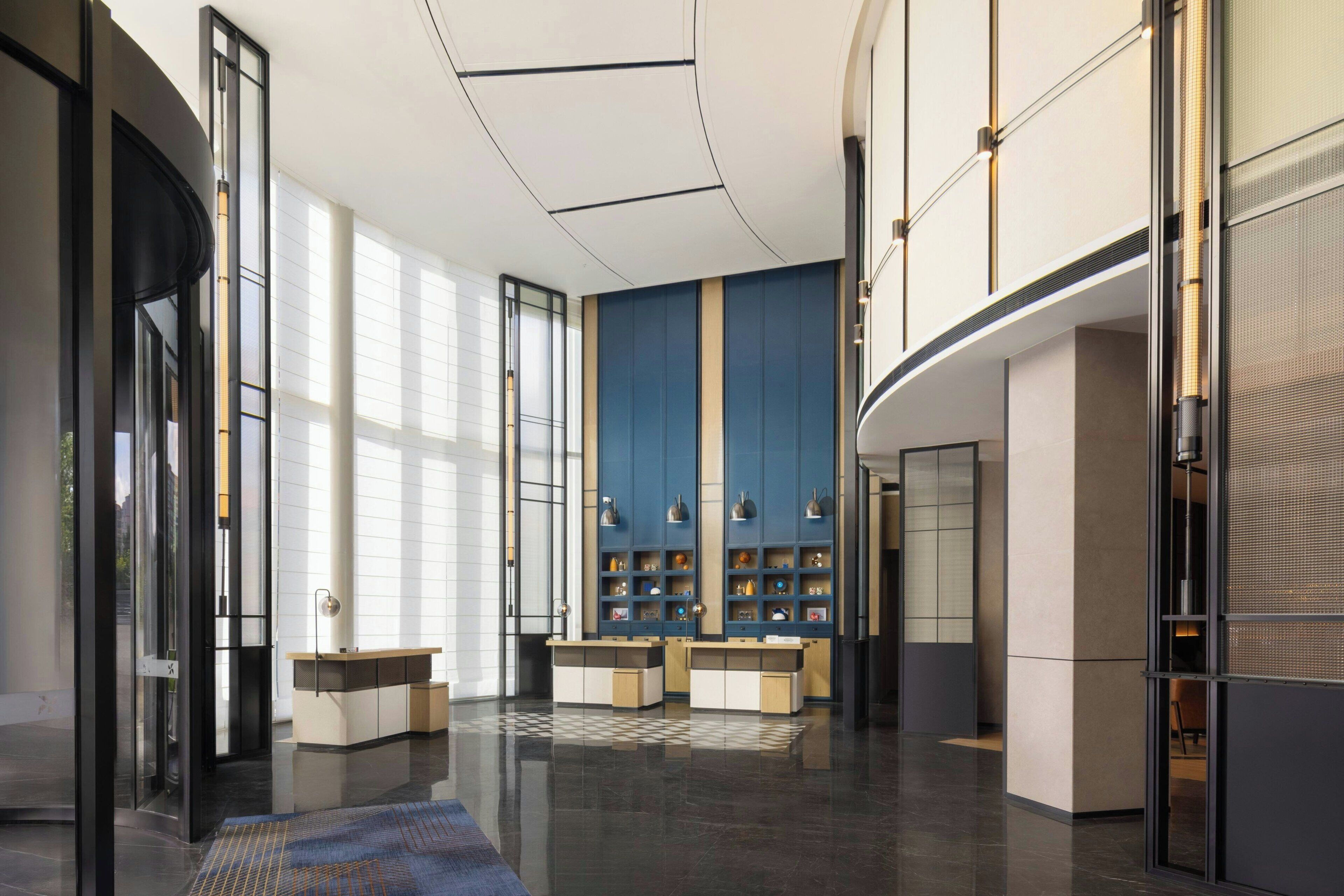 Een moderne lobby met een geruit vloerkleed, glazen deuren en een receptiebalie.