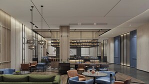 Un hall d’entrée spacieux, doté de hauts plafonds, d’un éclairage moderne et de différents types de sièges, notamment des canapés et des fauteuils.