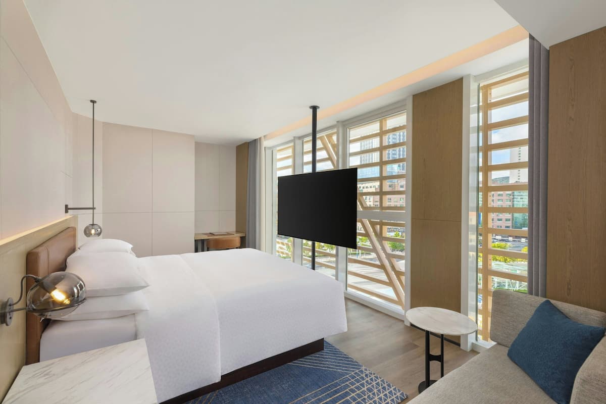 Een moderne hotelkamer met een groot bed, een televisie, een klein tafeltje en een bank.