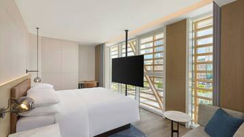 A modern hotel room with a large bed, a TV, a small table, and a sofa.