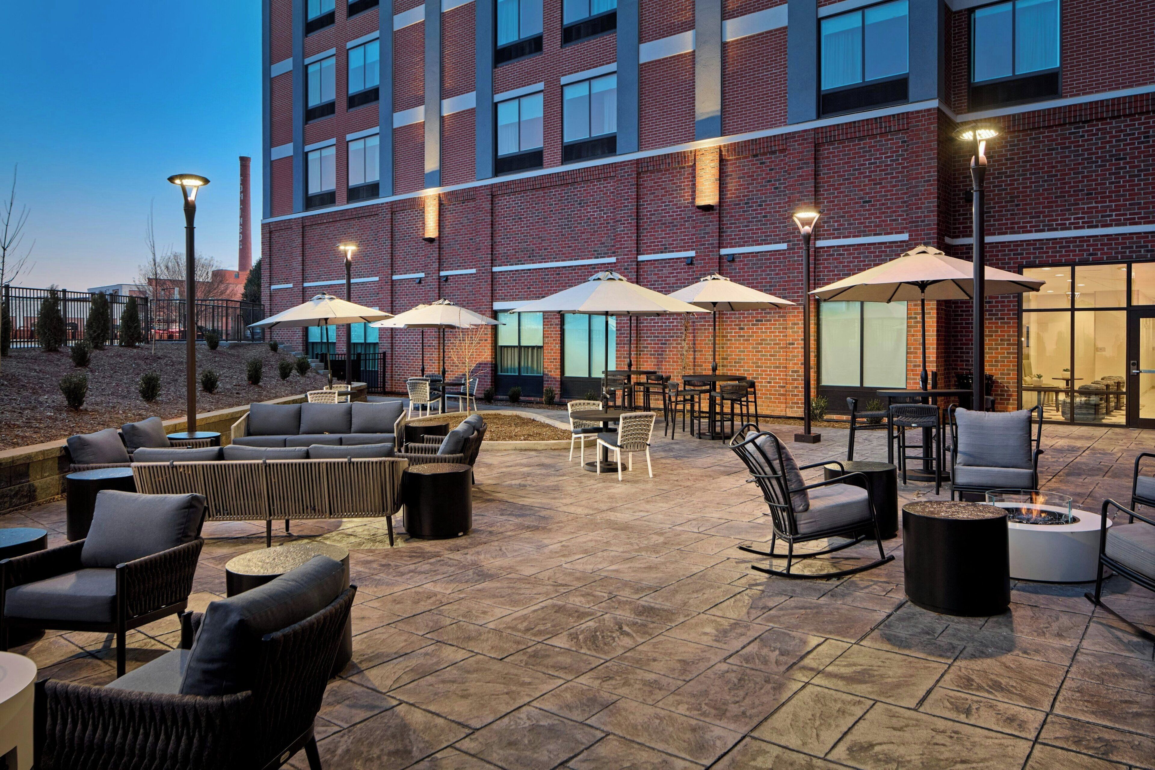 An outdoor patio with seating, umbrellas, and a fire pit.