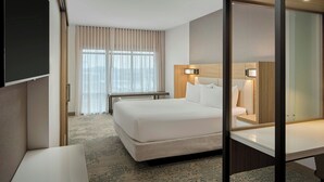 A hotel room with a large bed, a bedside table, a desk, and a window with curtains. - Springhill Suites By Marriott High Point Downtown (High Point)