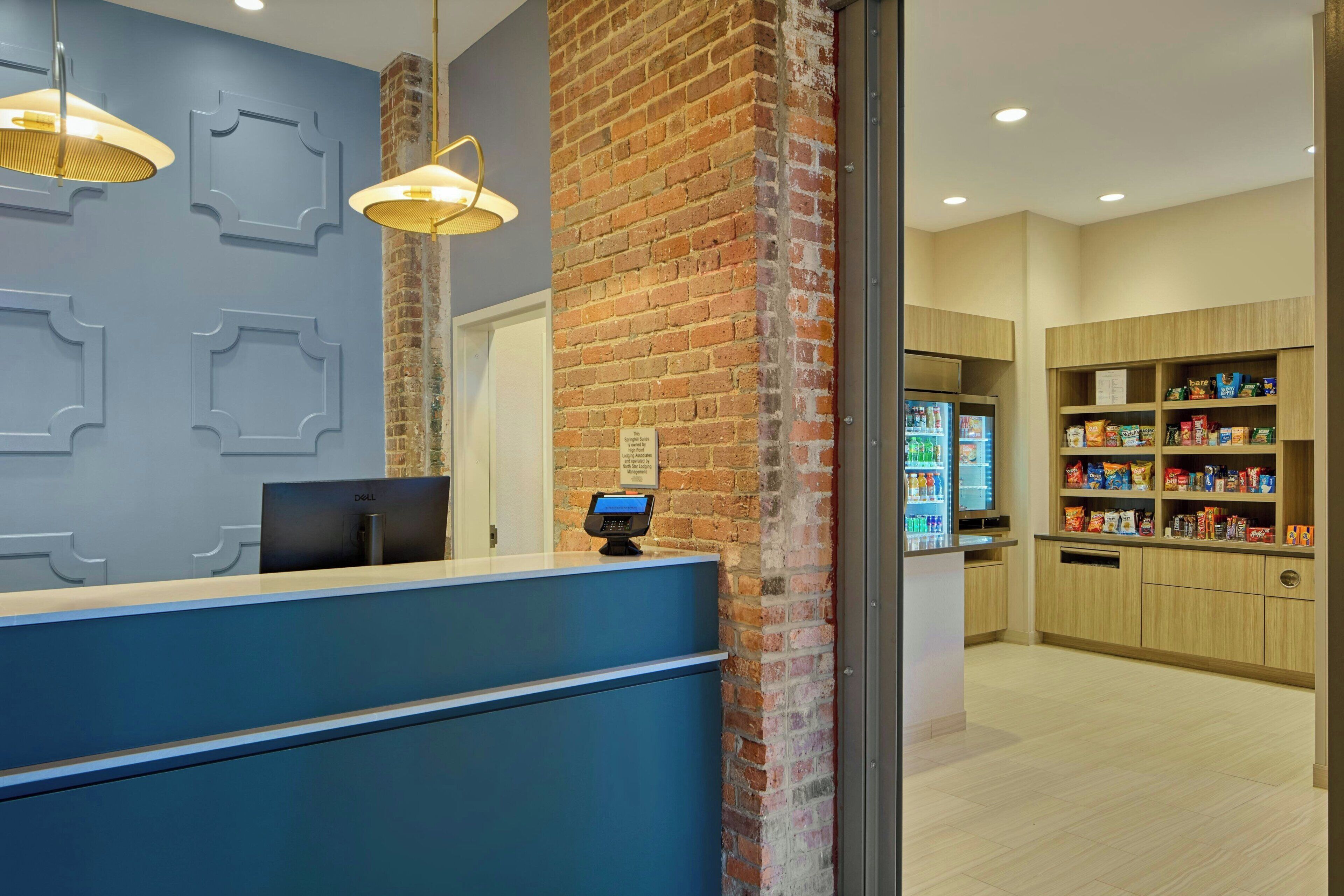 Een receptiebalie in blauw, een bakstenen muur, een Dell computer en een self-service kiosk.