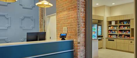 A reception area with a blue counter, a brick wall, a Dell computer, and a self-service kiosk.