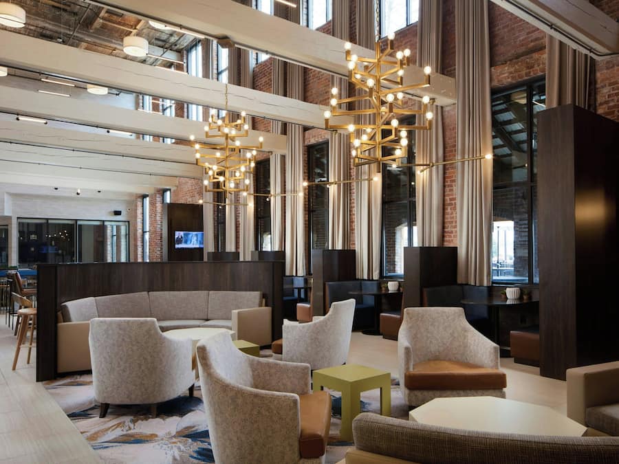 A spacious lobby with modern seating, large windows, and a brick wall.