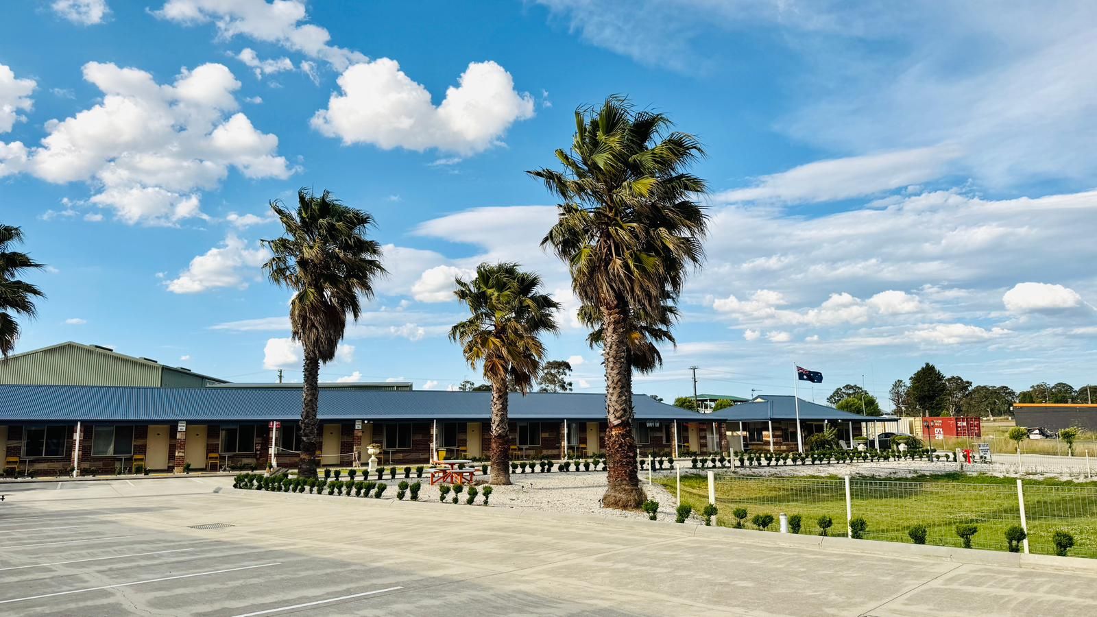 A building with a flat roof, large windows, and a paved parking area.