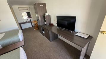 A compact hotel room with a bed, a kitchenette, a TV, and a small dining area.