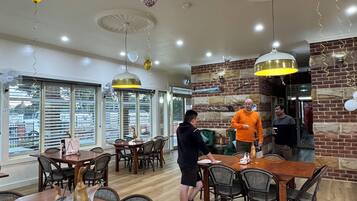 A spacious restaurant with high ceilings, wooden tables, and chairs.