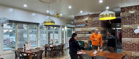 A spacious restaurant with high ceilings, wooden tables, and chairs.