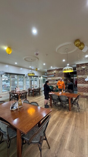 A spacious restaurant with high ceilings, wooden tables, and chairs. - Marulan Motor Inn (Marulan)