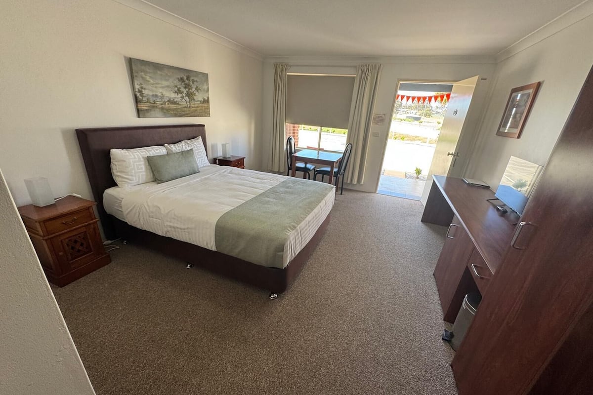 A neatly arranged bedroom with a large bed, bedside tables, a desk, and a chair.